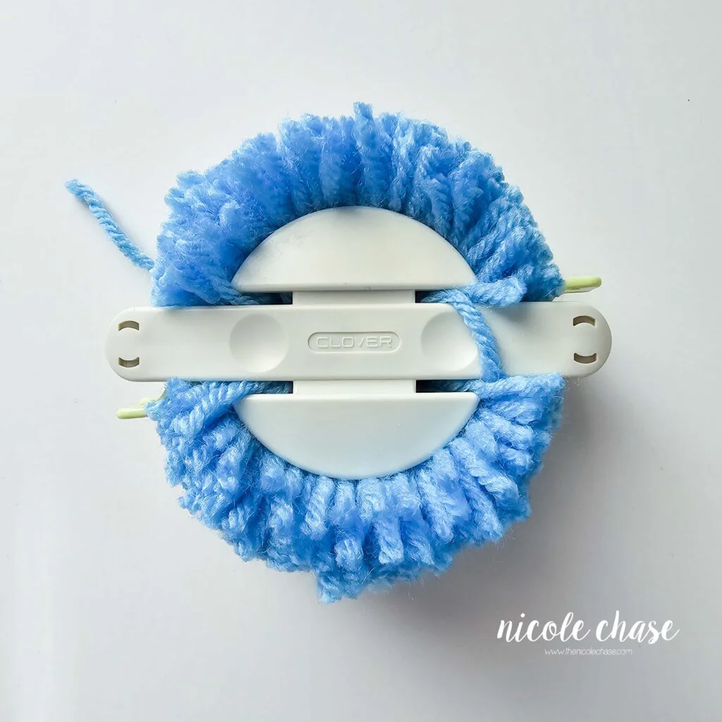 The blue yarn in the pom maker has been cut all the way around. 