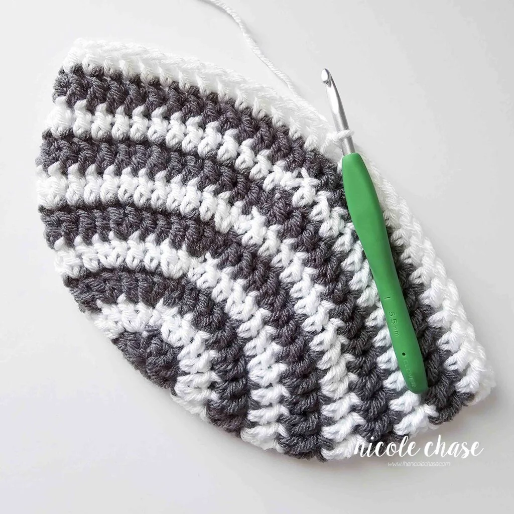 Tutorial image showing the progress of the Spirit Earflap Hat; the crown is striped gray and white. 