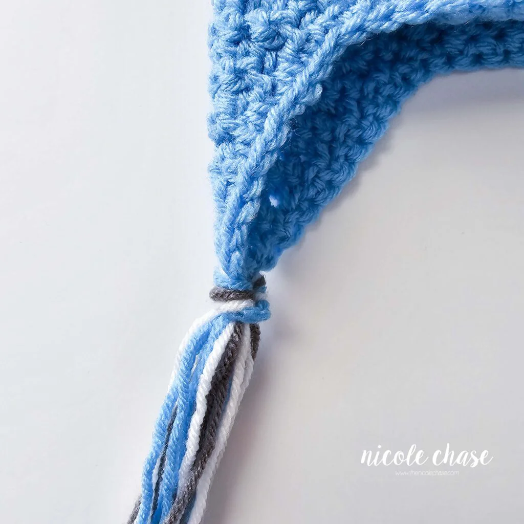 The strands of yarn for the tassels have been attached to the earflap on this free hat crochet pattern. 