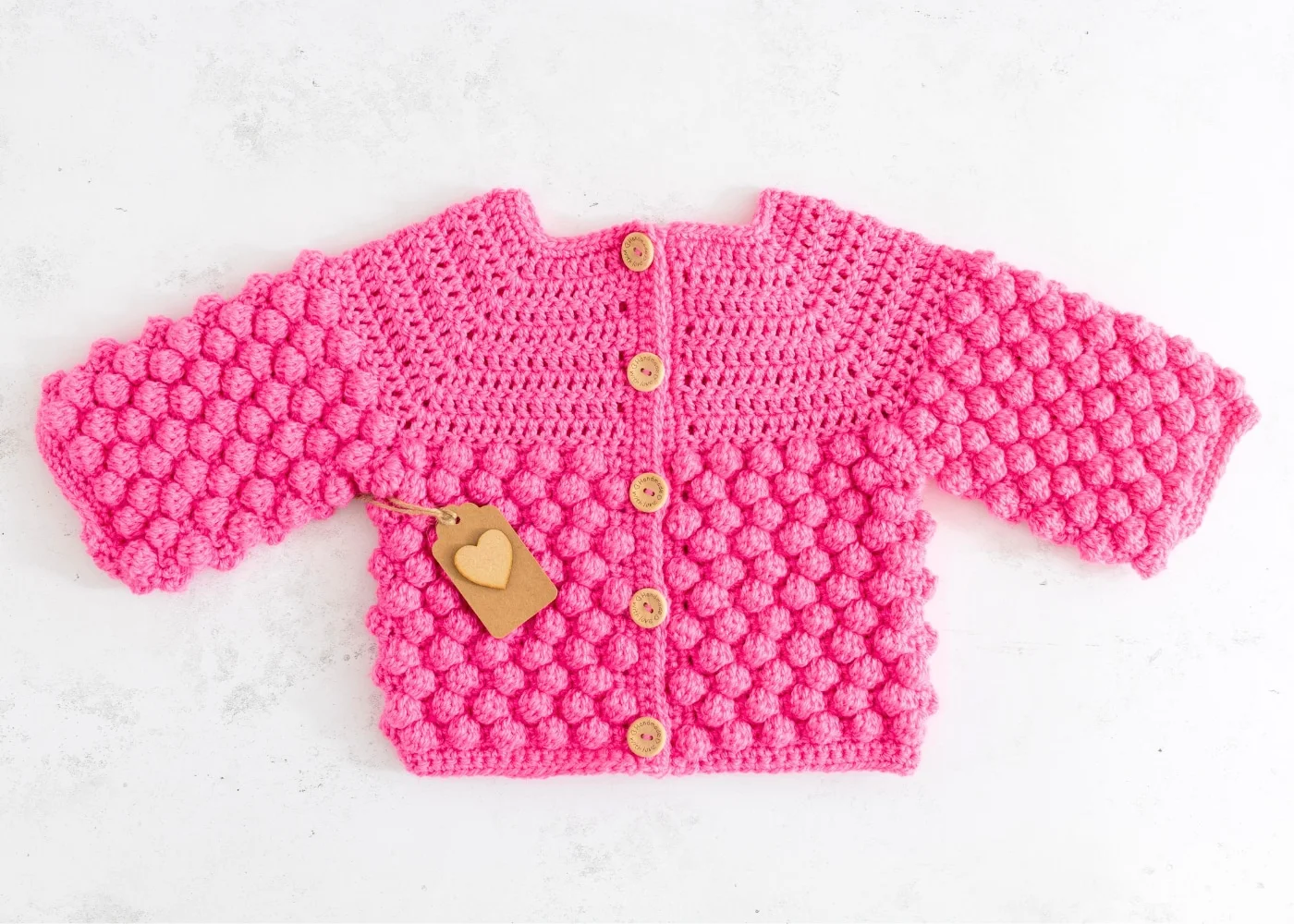 Bobble Crochet Baby Cardigan Pattern free pink colour on table